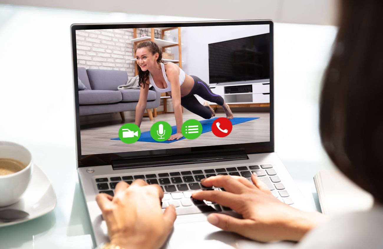 Frau schaut sich auf Laptop ein Video einer Frau beim Yoga an.