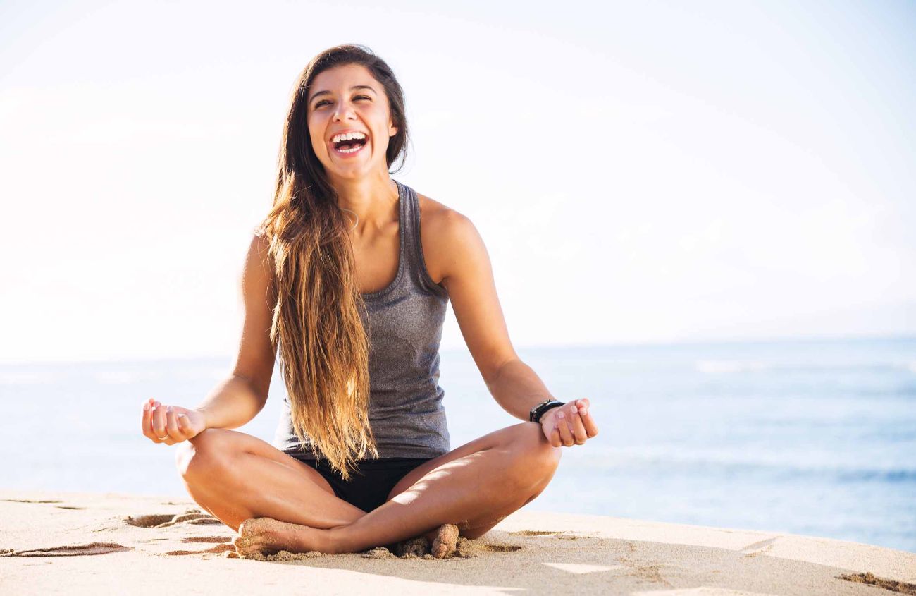 Yoga gegen Verstopfung: Junge Frau meditiert am Strand