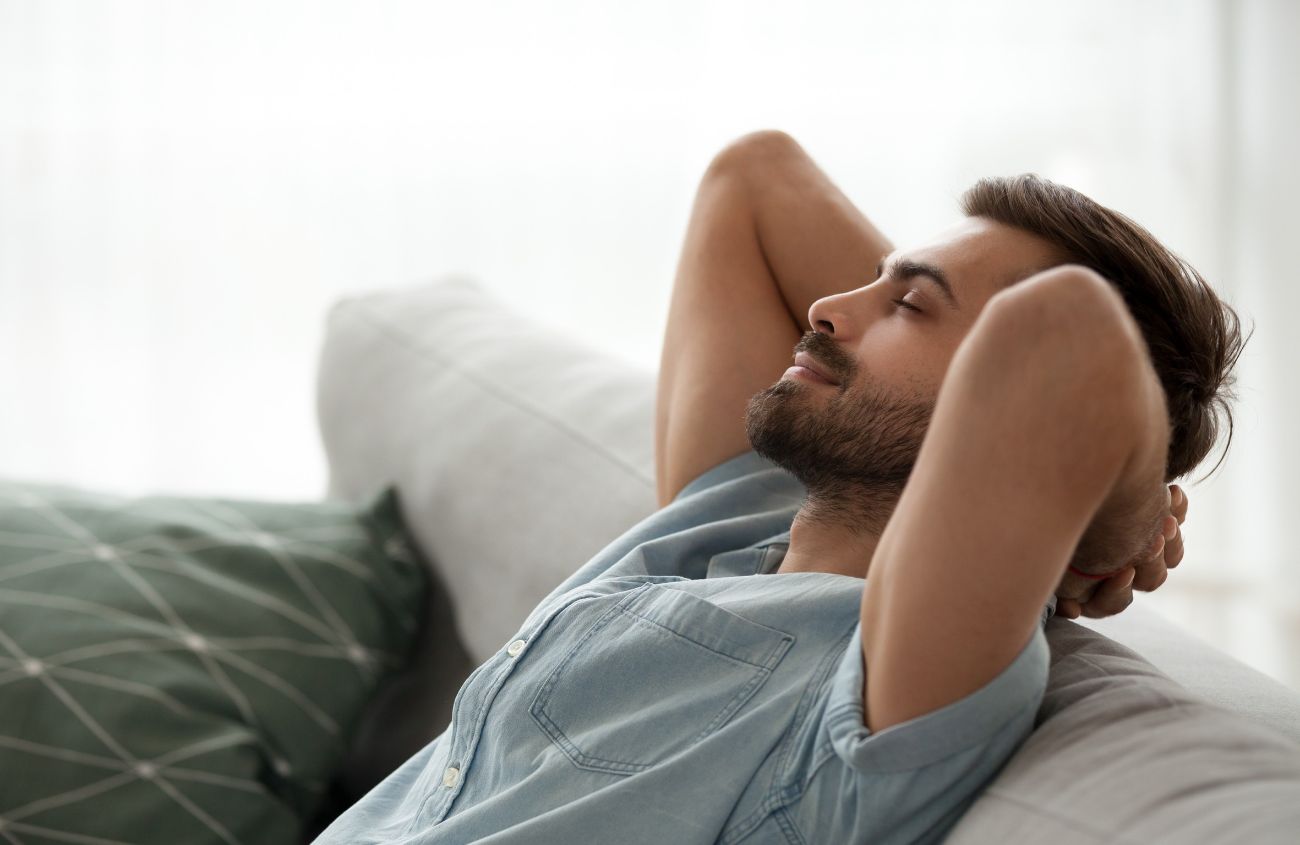 Mann der glücklich auf dem Sofa sitzt