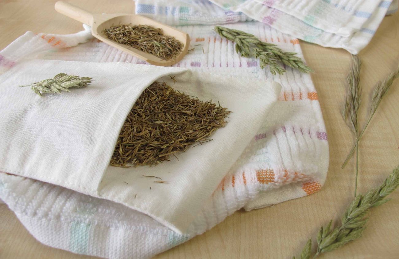 Ein Heublumensack gegen Bauchschmerzen liegt auf einer hölzernen Oberfläche