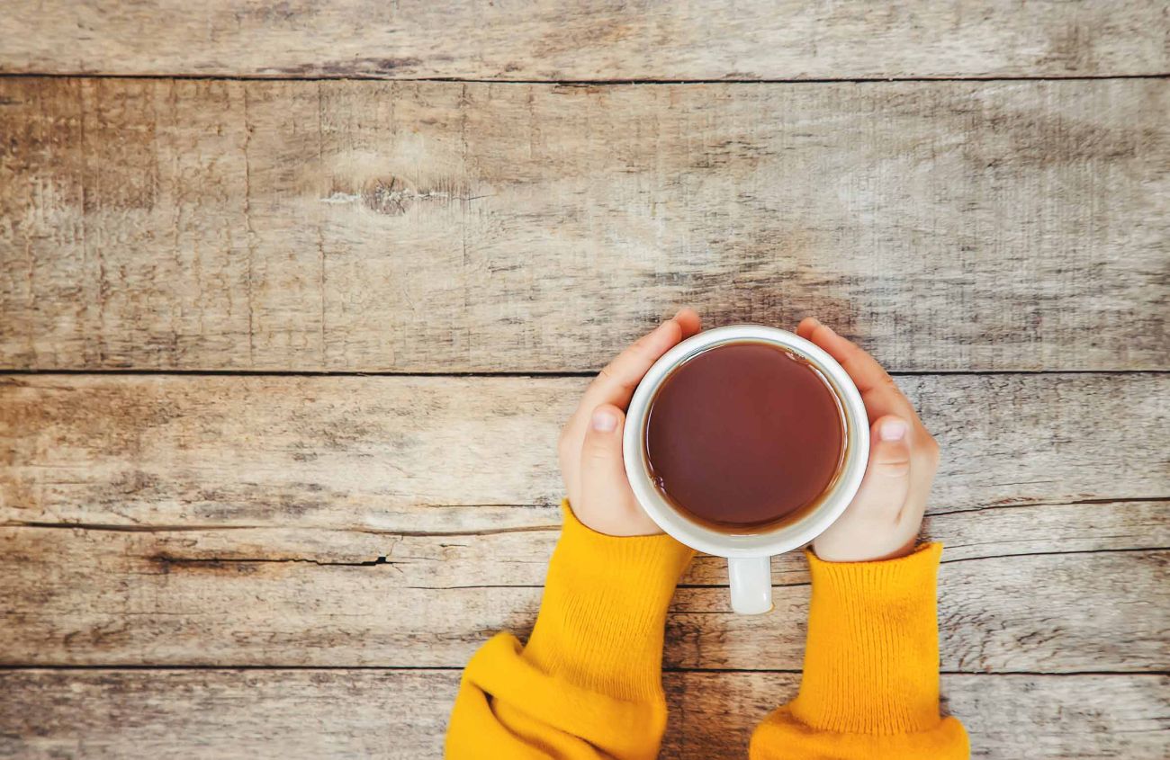 Gegen Bauchschmerzen, volle Tasse Tee in den Händen eines Kindes