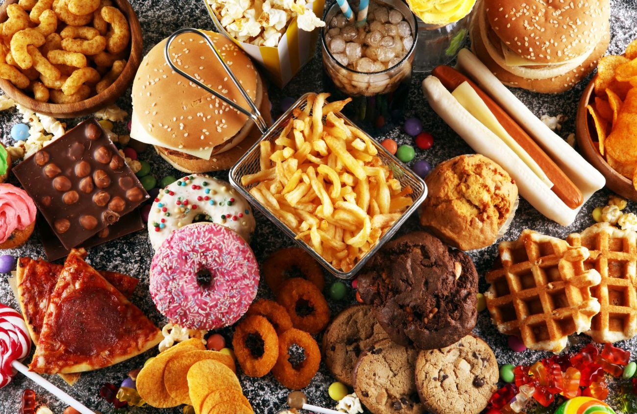 Ein Tisch voller fettreicher Lebensmittel wie Donuts und Pommes, die zu Magenverstimmung führen können.