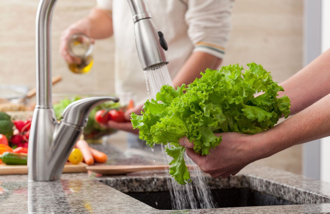 Gegen Magenverstimmung: Ein Salatkopf wird unter den Strahl eines Wasserhahns gewaschen.