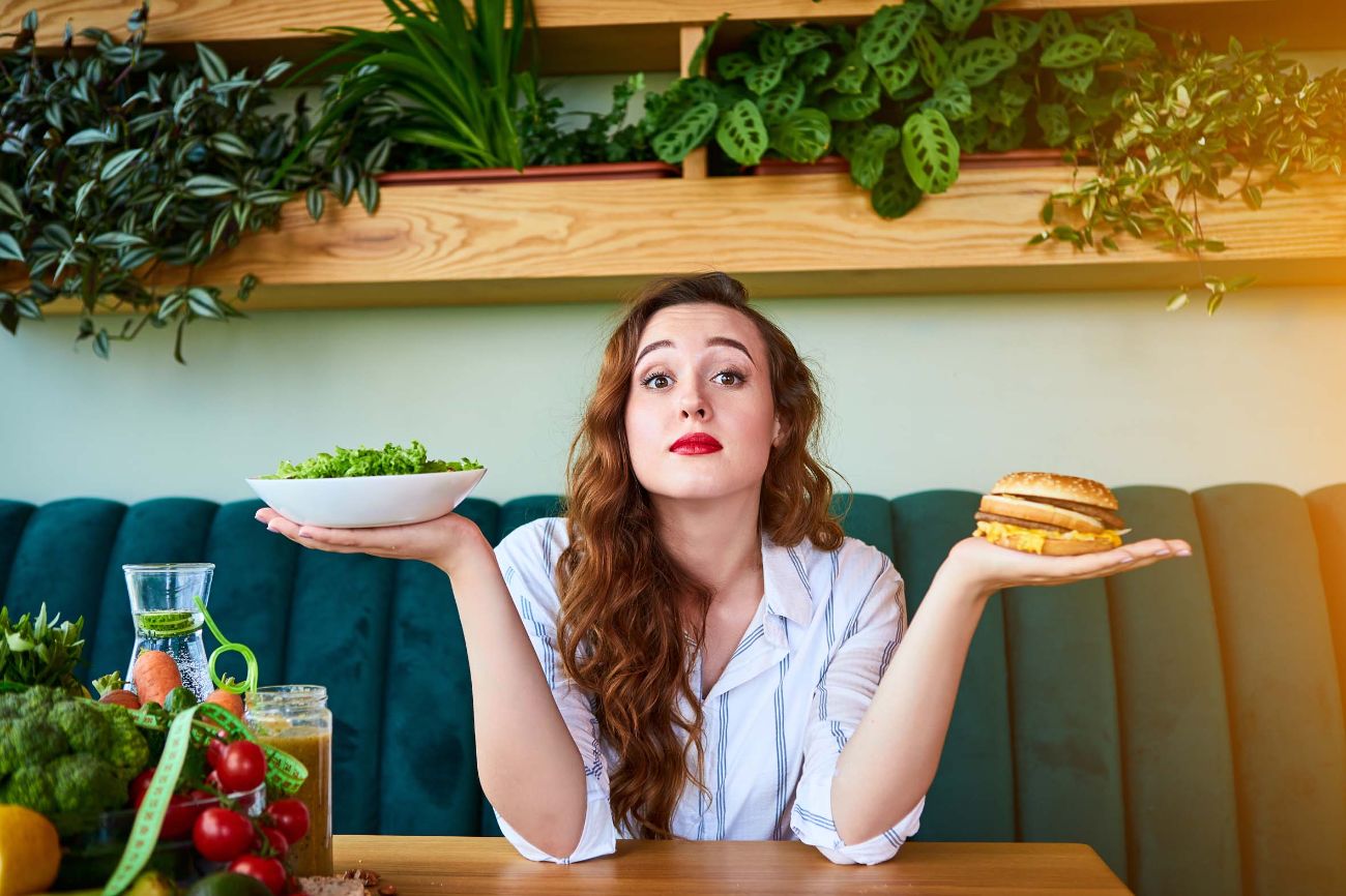 Frau hat die Qual der Wahl zwischen Burger und Salat.