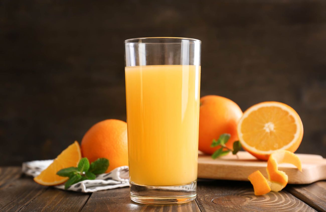 Depression durch zu wenig trinken: Ein Glas Orangensaft vor einigen Orangen