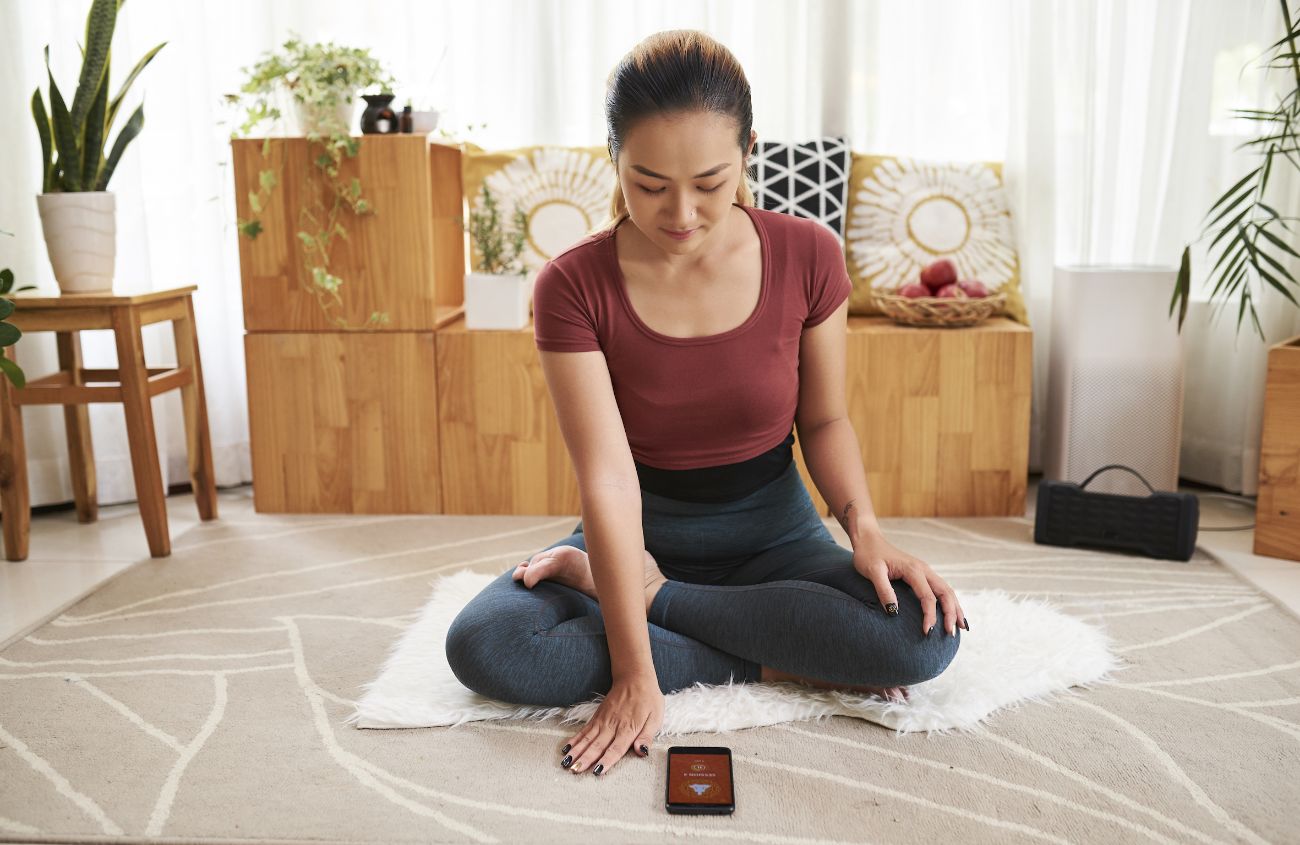 Frau die mit ihrem Handy Yoga macht