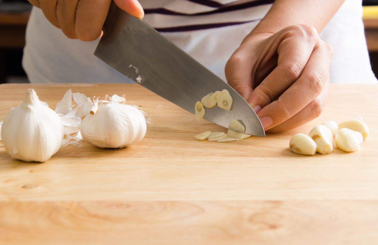 Hausmittel gegen Magenschleimhautentzündung, Person hackt Knoblauch klein