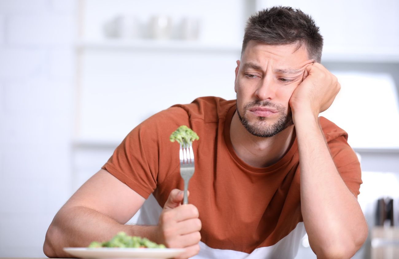 Magenschleimhautentzündung, Mann schaut sein Essen angewidert an