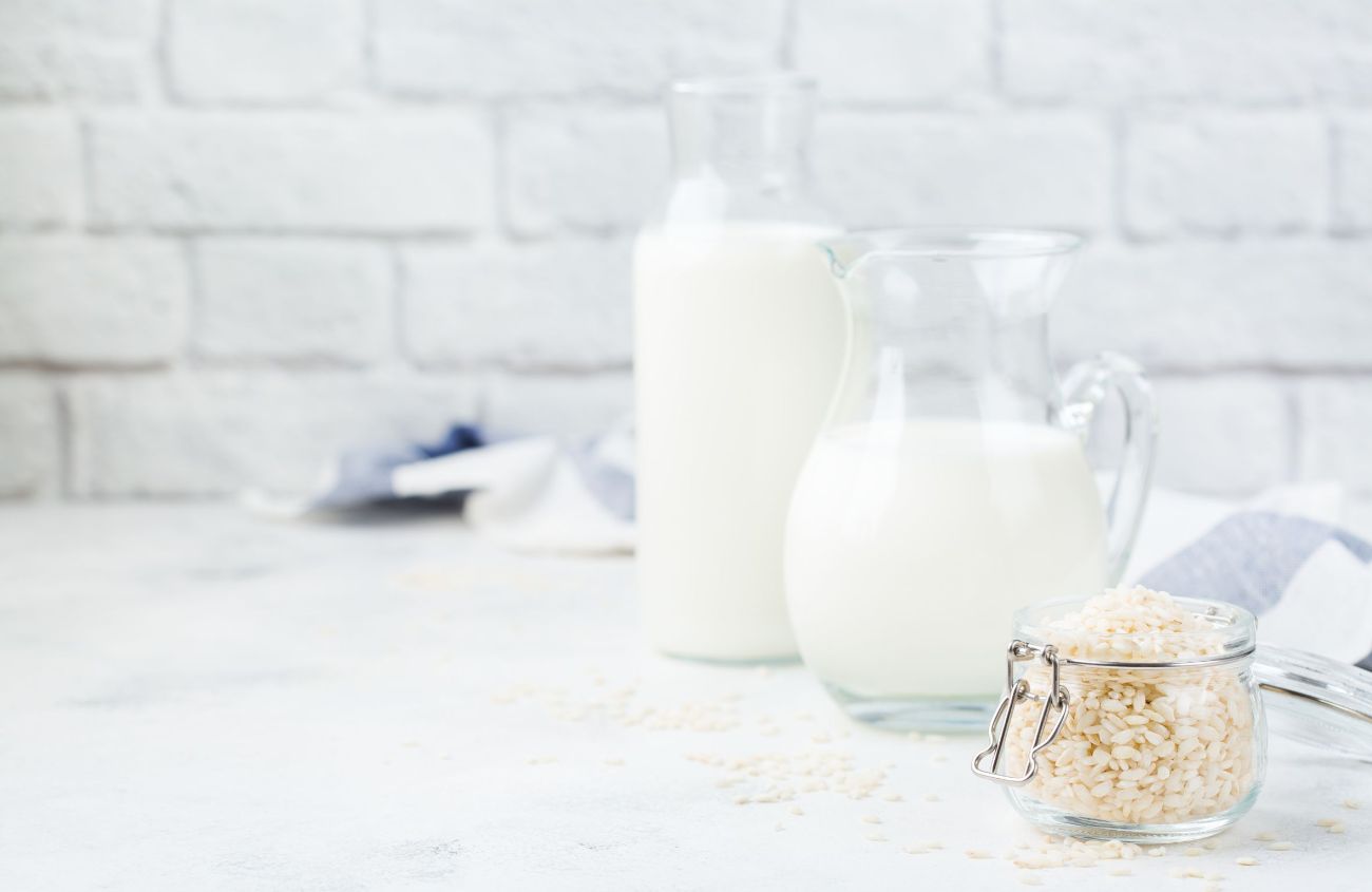 Milch-Alternative: Ein Glas Reis und zwei Karaffen voll Reismilch