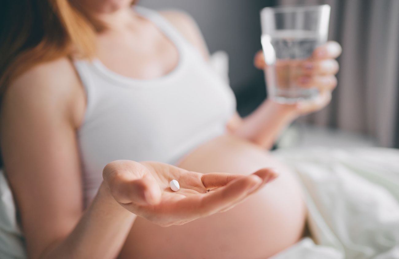 Eine schwangere Frau mit einem Nahrungsergänzungsmittel in der Hand