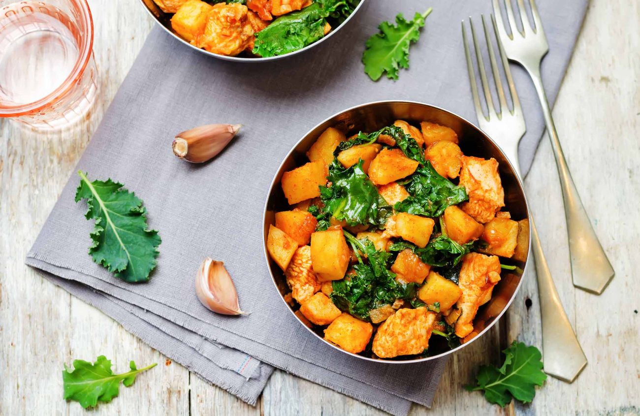 Unverträglichkeiten: Kartoffel-Curry-Gericht mit Huhn auf hölzernem Untergrund