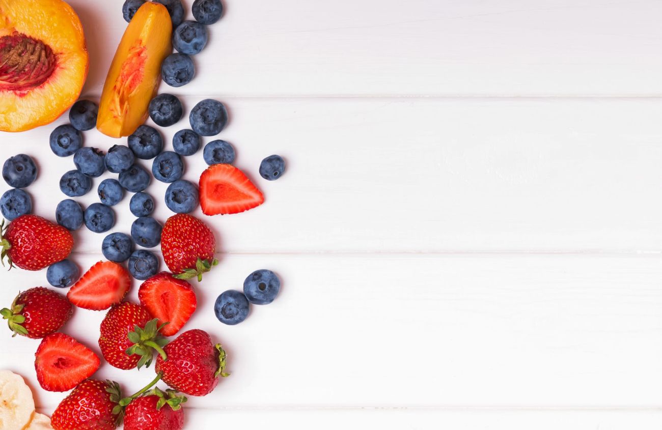 Unverträglichkeiten: Früchte und Beeren auf weißem Holztisch, Draufsicht