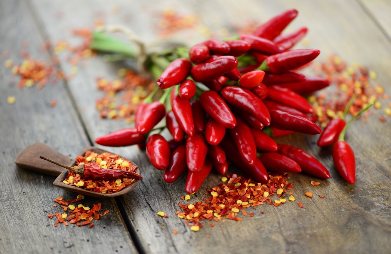 Paprika-Unverträglichkeit: Rote Chilli-Schoten auf einem Holztisch