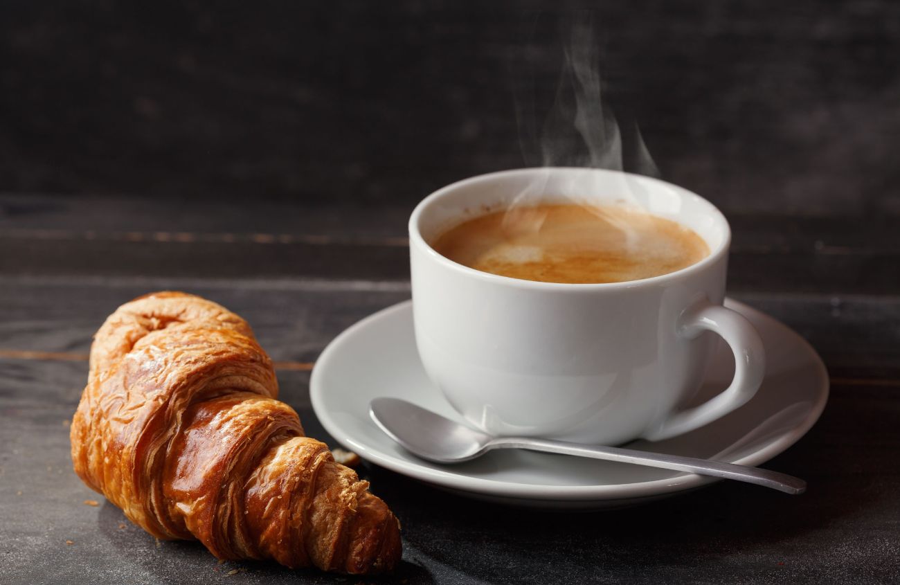 Eine Tasse Kaffe mit einem Croissant.