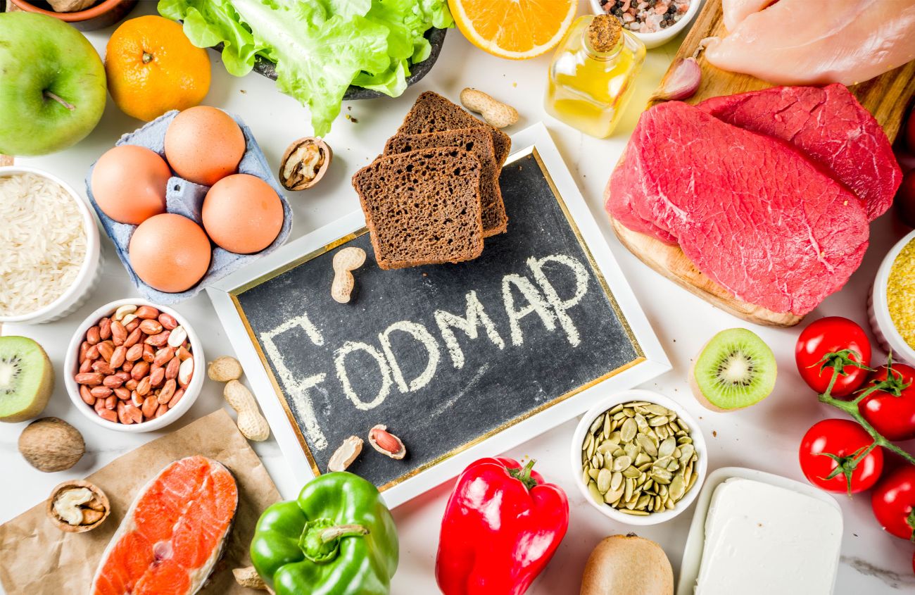 Eine Schiefertafel, auf der Fodmap steht, liegt inmitten verschiedener Lebensmittel.
