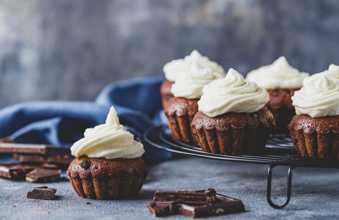 Braune Cupcakes mit weißem Frosting und Schokostücken.