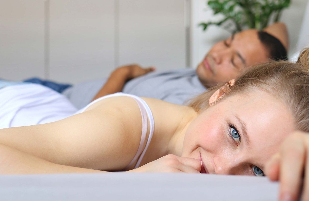 Rückenschmerzen durch Blasenentzündung, Frau liegt im Bett und lächelt