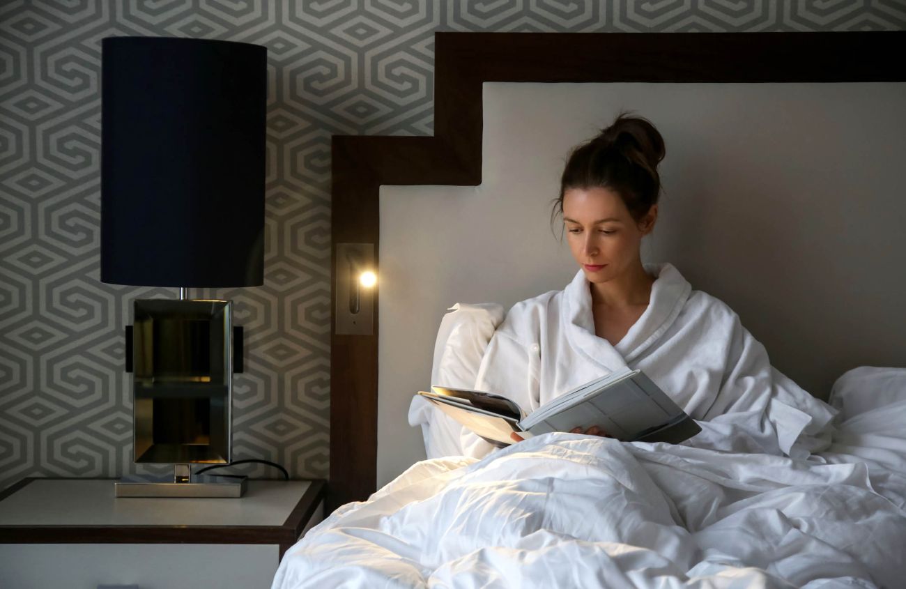 Erholung statt Stress, Frau liegt im Bett und liest ein Buch