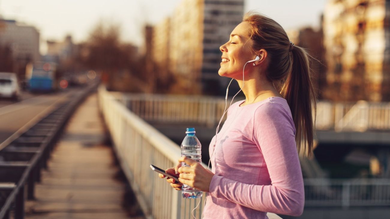 Sport und Verdauung, Joggerin bleibt stehen und genießt die Sonne