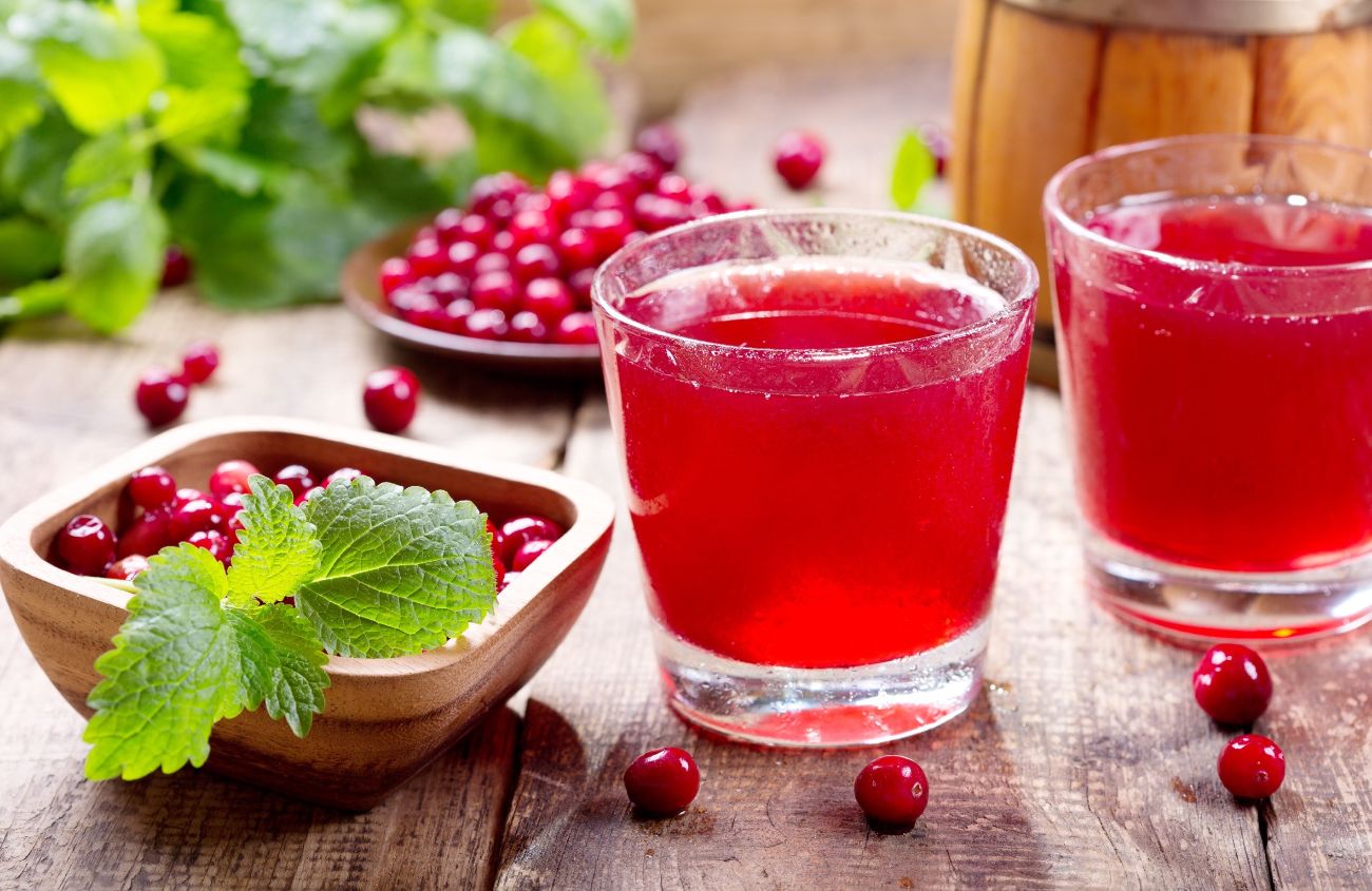 Ständig Blasenentzündung: Gläser mit Cranberrysaft auf einem Holztisch