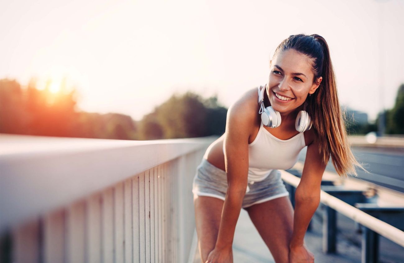 Stoffwechselstörung, Joggerin ruht sich aus und blickt in die Sonne