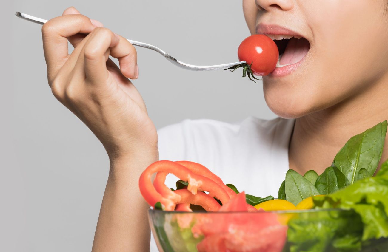 Wie funktioniert die Verdauung, Frau mit Salat isst eine Tomate