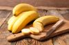 Eine aufgeschnittene Banane auf einem Brett und weitere Bananen dahinter