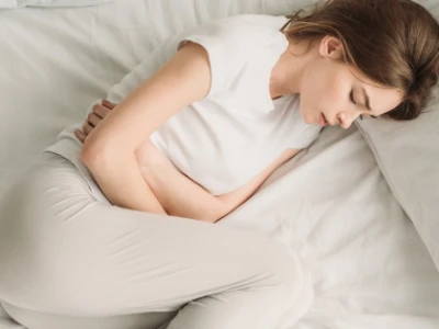 Chronische Bauchschmerzen ohne Befund, liegende Frau hält sich den Bauch