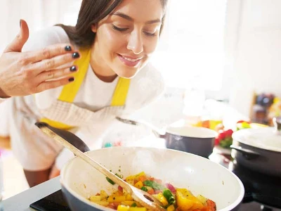 Magenschonende Rezepte, Frau riecht an ihrer Gemüsepfanne