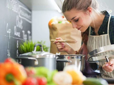 Rezepte bei Speiseröhrenentzündung, Frau rieht an ihrem Essen, das im Topf auf dem Herd steht