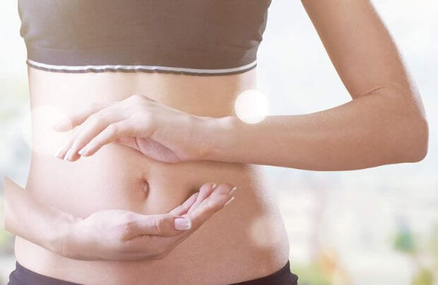 Mikrobiom, junge Frau hält Hände in Balance vor ihren Bauch.