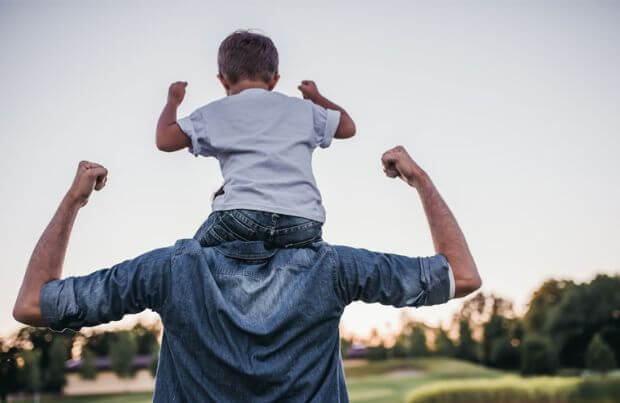 Vater mit Sohn auf der Schulter in Siegerpose.