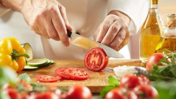Ernährung bei Nierensteinen; Mann schneidet Tomaten